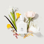 Creed Love in White perfume bottle with flowers and vanilla beans on a light background
