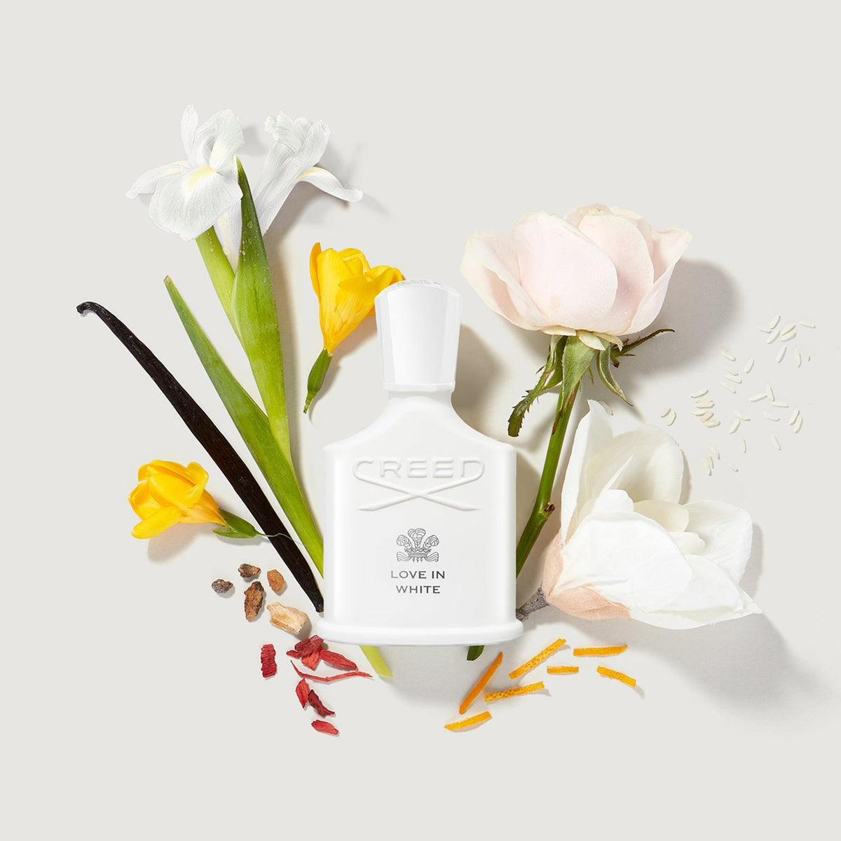 Creed Love in White perfume bottle with flowers and vanilla beans on a light background