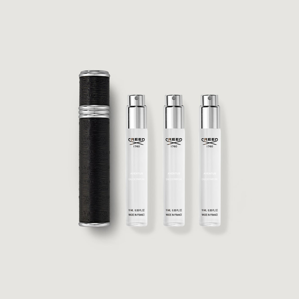 Set of Creed perfume bottles on a light gray background