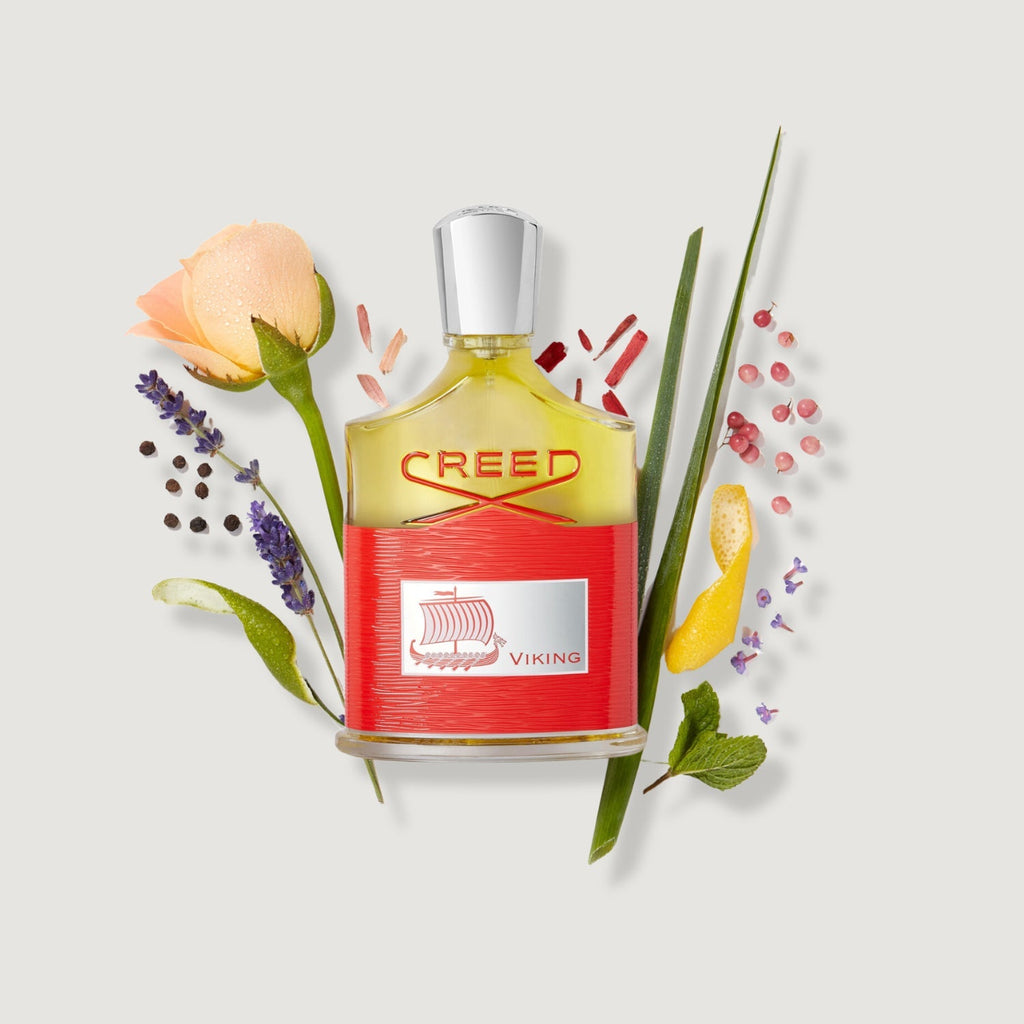 Creed perfume bottle with flowers and leaves on a light gray background