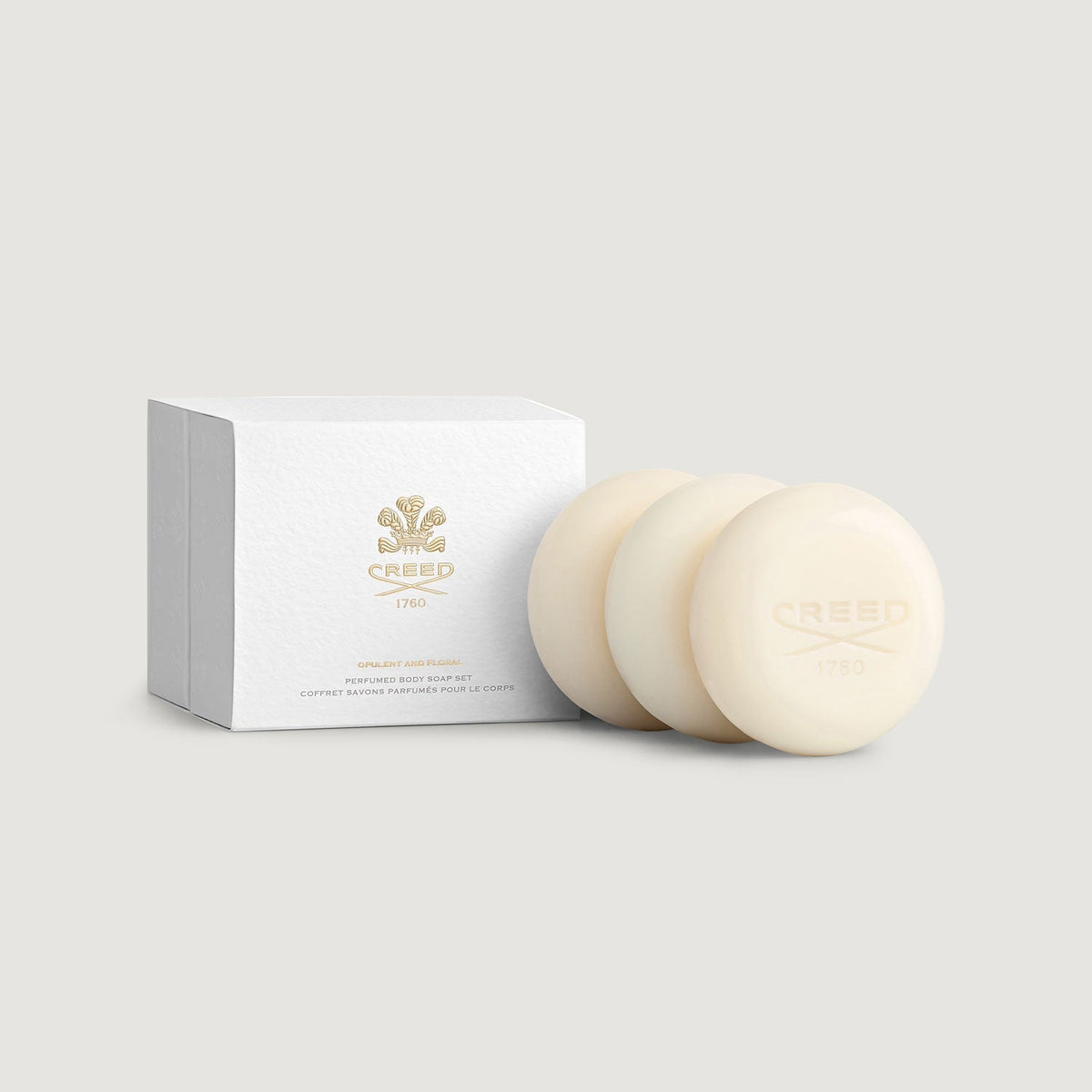 Two cream-colored soaps with a white box labeled 'Creed' on a light gray background