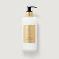 White lotion bottle with gold label on a light gray background