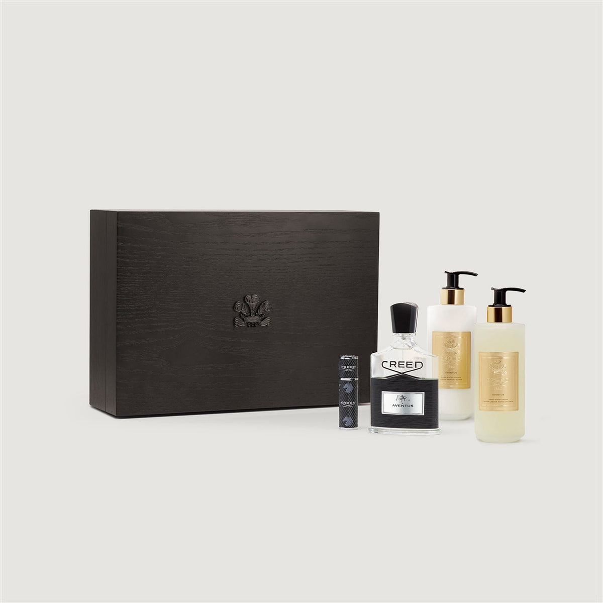 Set of Creed beauty products including a black box, bottles, and a small bottle on a light gray background