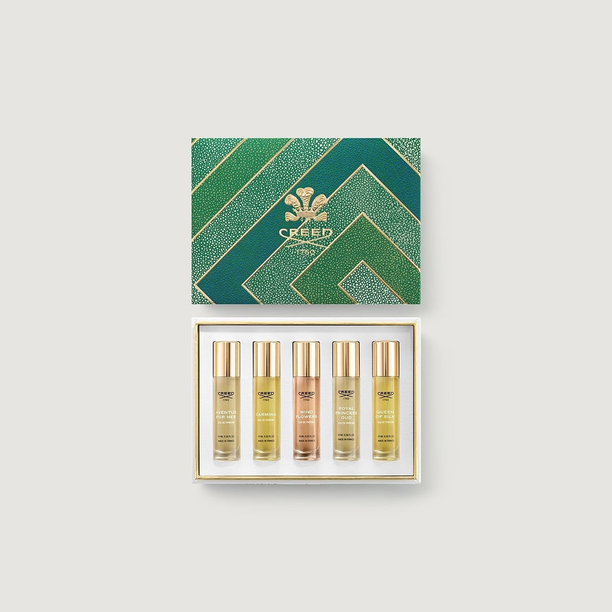 Set of Creed perfume bottles in a decorative box on a light gray background