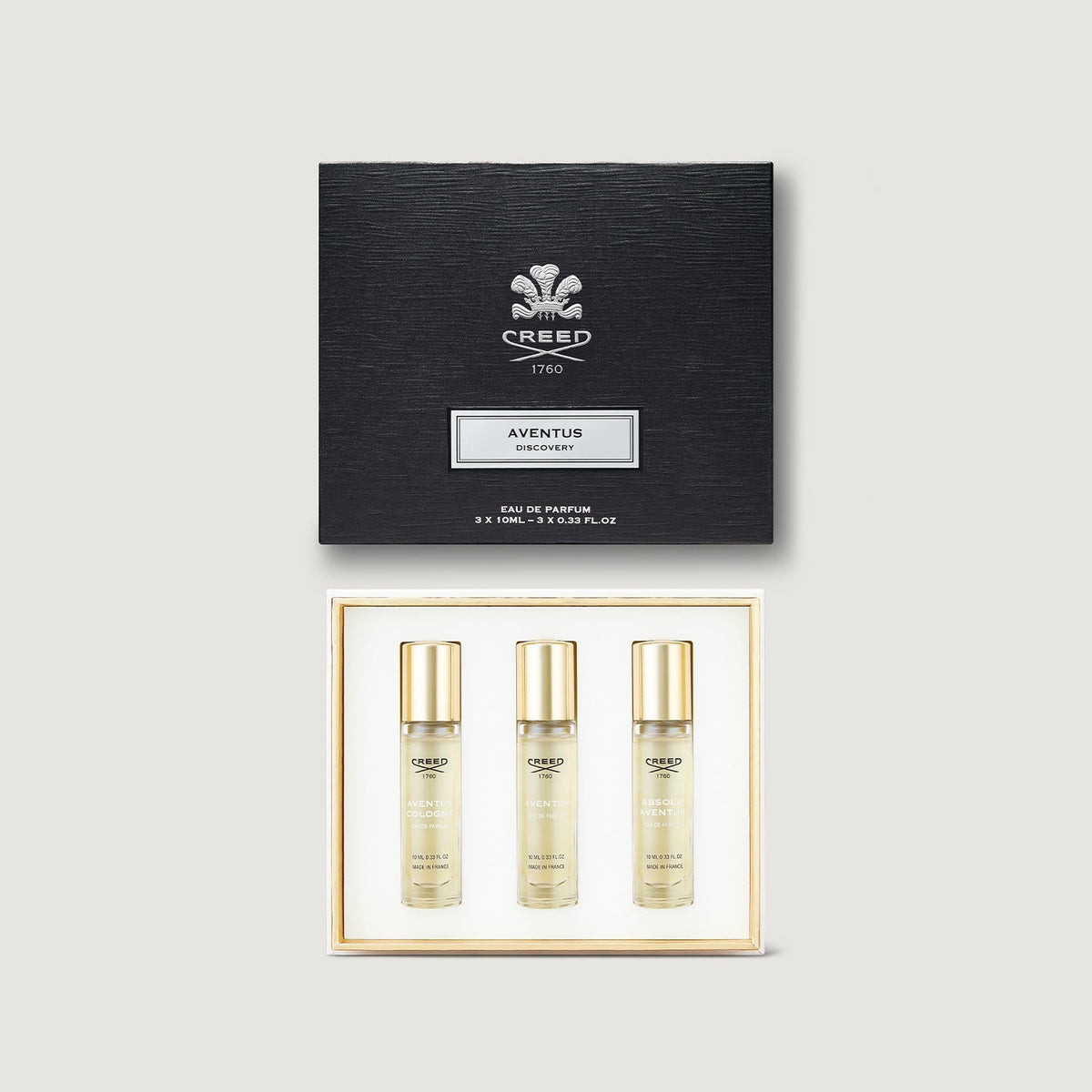 Creed Aventus perfume set with three bottles and a black box on a light gray background