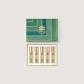 Set of five gold bottles with a green Creed box on a light gray background