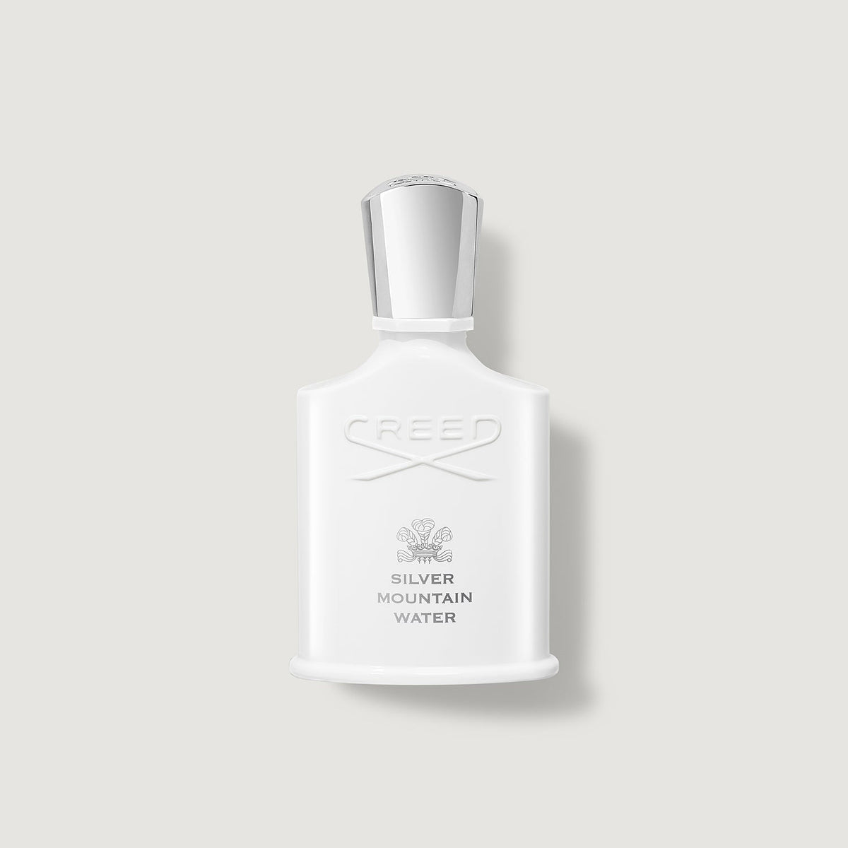 White Creed perfume bottle with silver cap on a light gray background